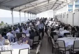 Attendees at round tables under a tent at an investor event