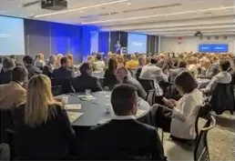 A large audience at round tables facing the stage
