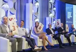 A panel scoring pitches with numbered paddles on stage