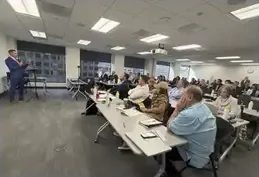 A workshop room with attendees at long tables